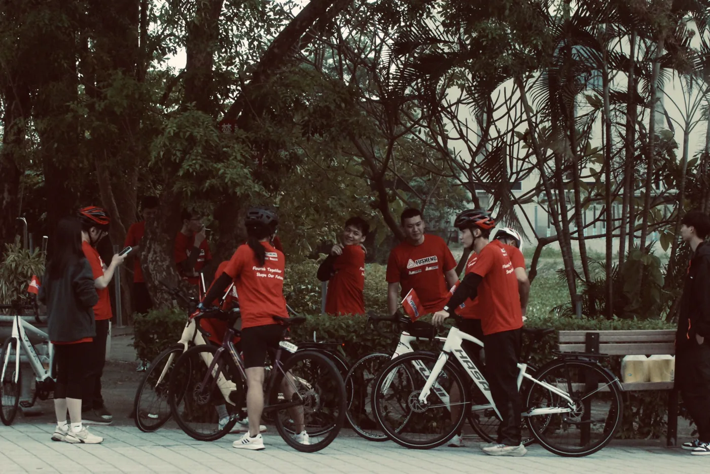 參加者在公園樹蔭下停車休息、整隊，旁邊靠著數台單車
