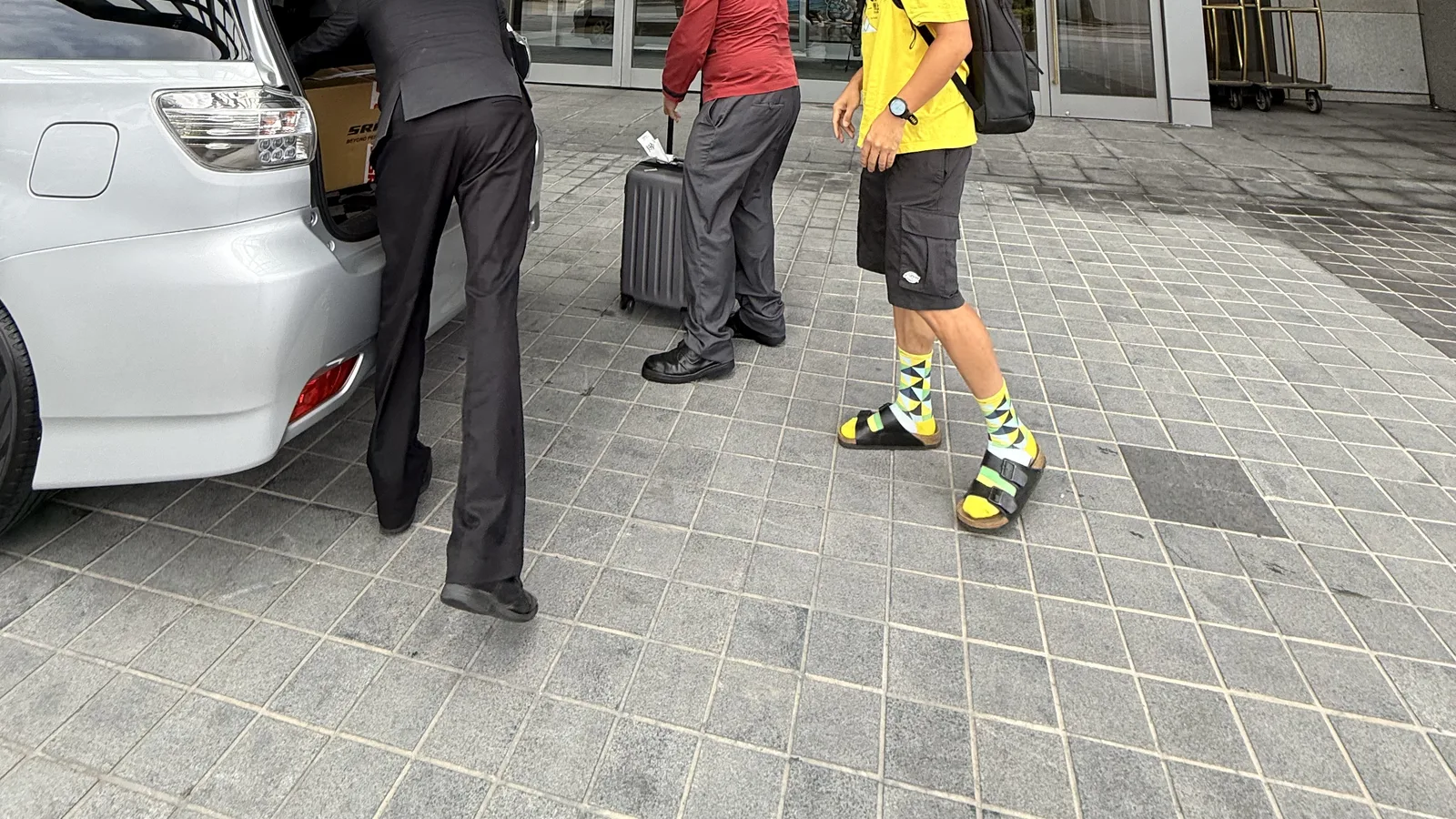 金湖飯店門口，飯店人員從接駁車後廂搬下裝箱的自行車與行李