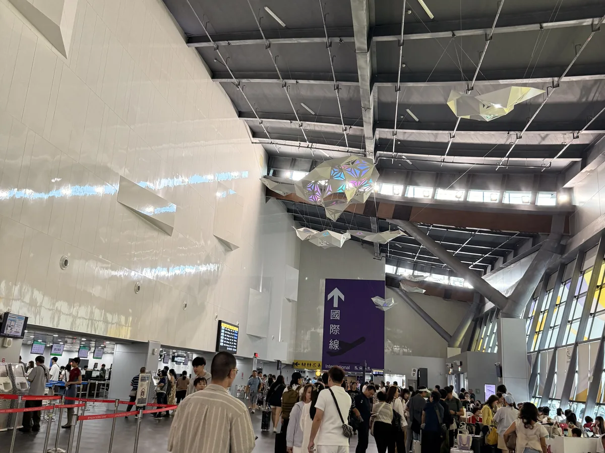 臺中國際機場出境大廳的報到櫃檯與行李託運區,排隊的旅客與行李推車