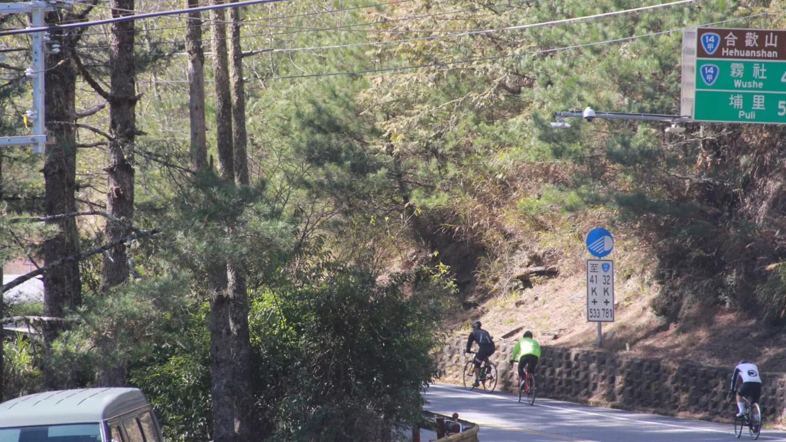 三位公路車騎士爬行台14甲線,路旁指標寫著合歡山、霧社與埔里