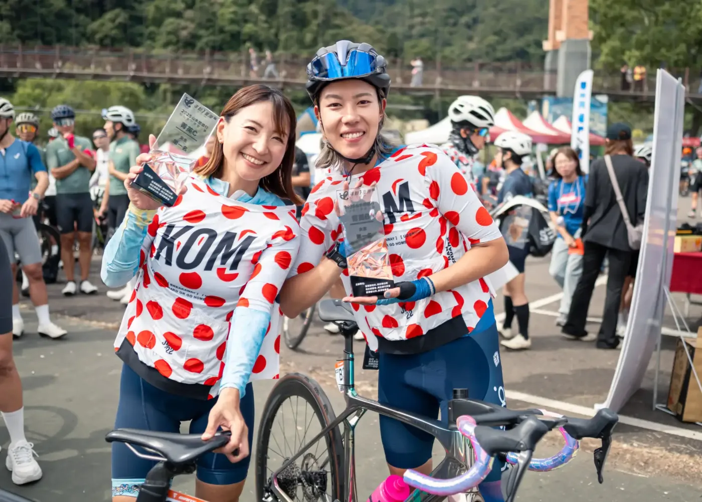 兩位穿著紅點爬坡王車衣的女子選手在南庄會場手持獎座合影