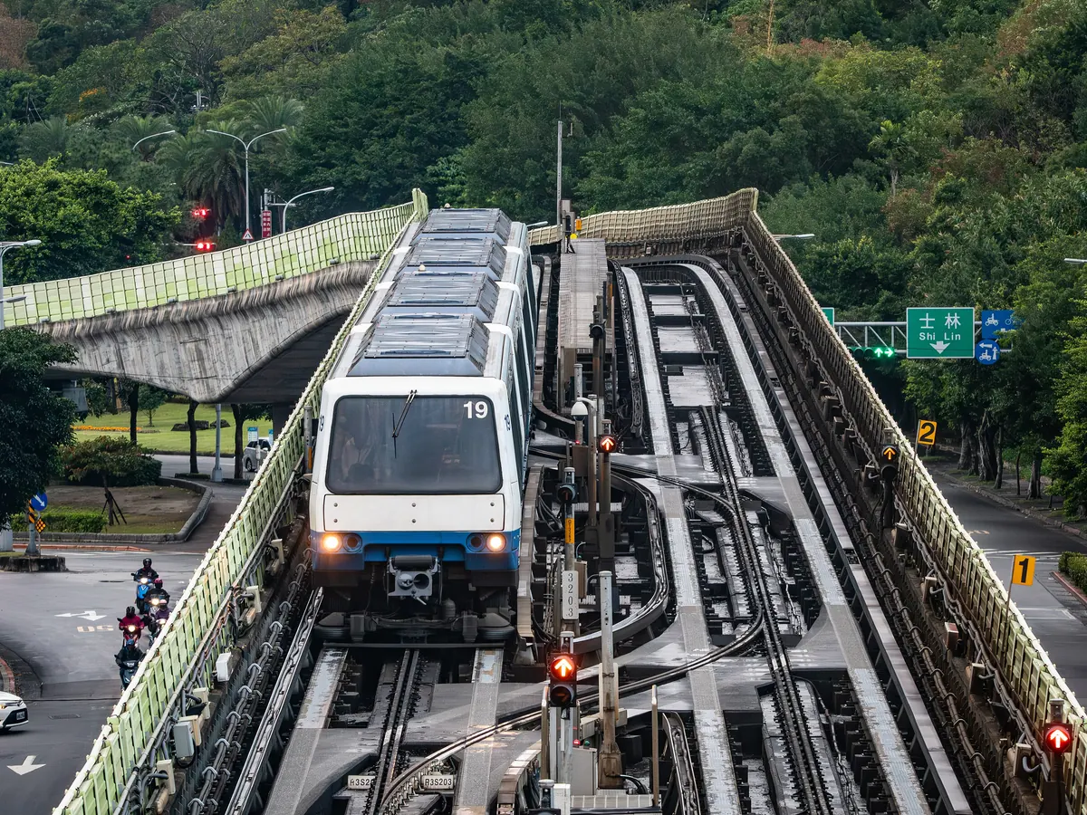 文湖線 VAL256 電聯車行駛於高架軌道，旁有往士林的路標